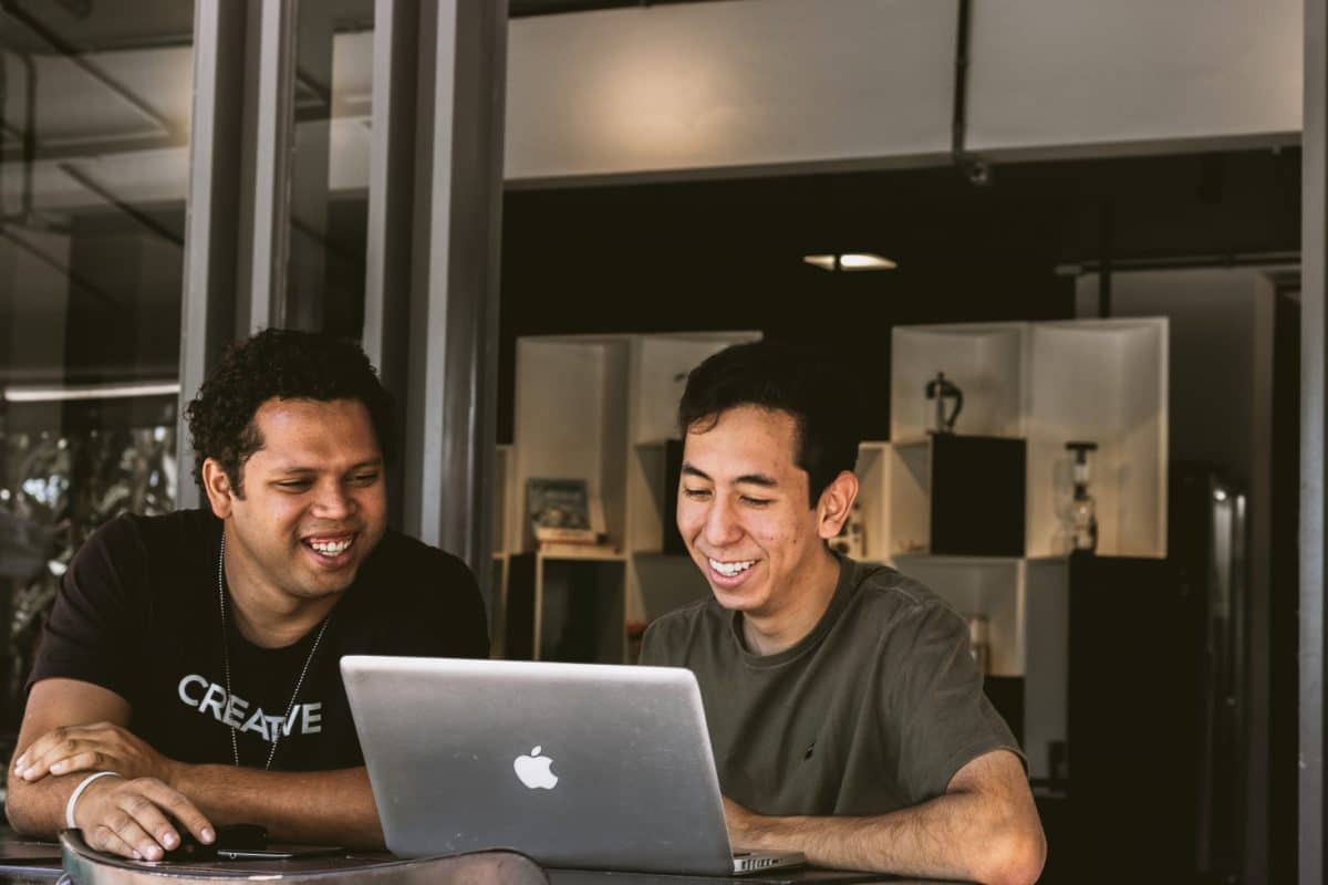 Two people sat smiling at one of the persons laptop