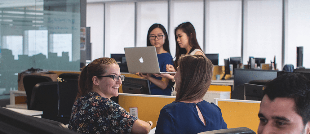 Image shows a group of people in the office, working together.